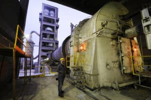Cement factory with worker standing by material that uses abrasion anchors for holding refractory material.