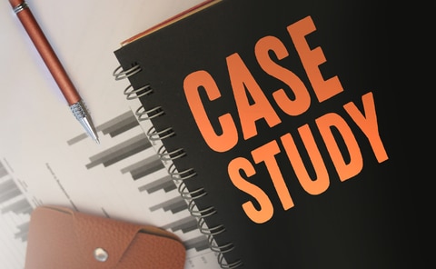 Case Study diary in black with orange letter laying on desk with pencil. Anchoring design case studies.